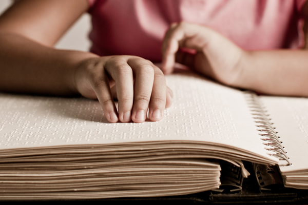 A girl reading a Braille book.